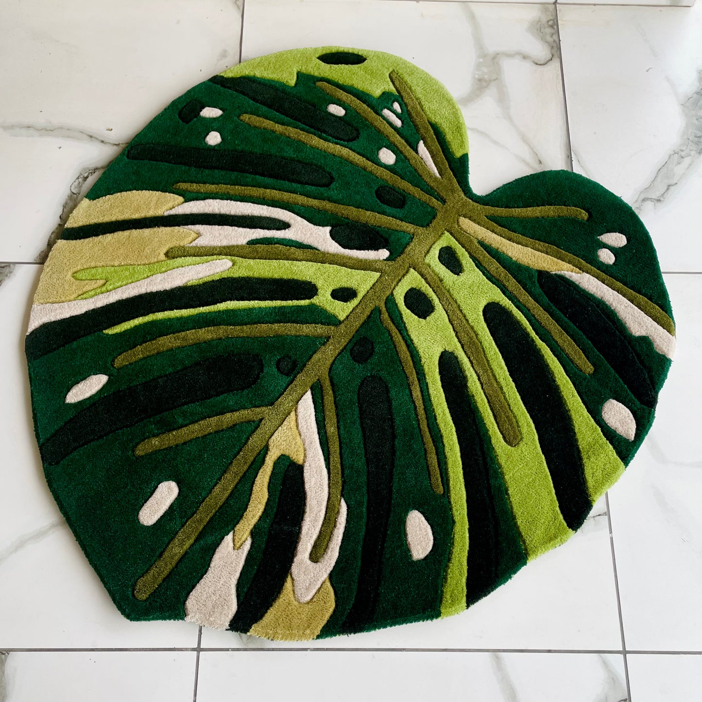 Botanical-themed rug featuring Monstera leaf design in rich green tones with distinctive holes and splits