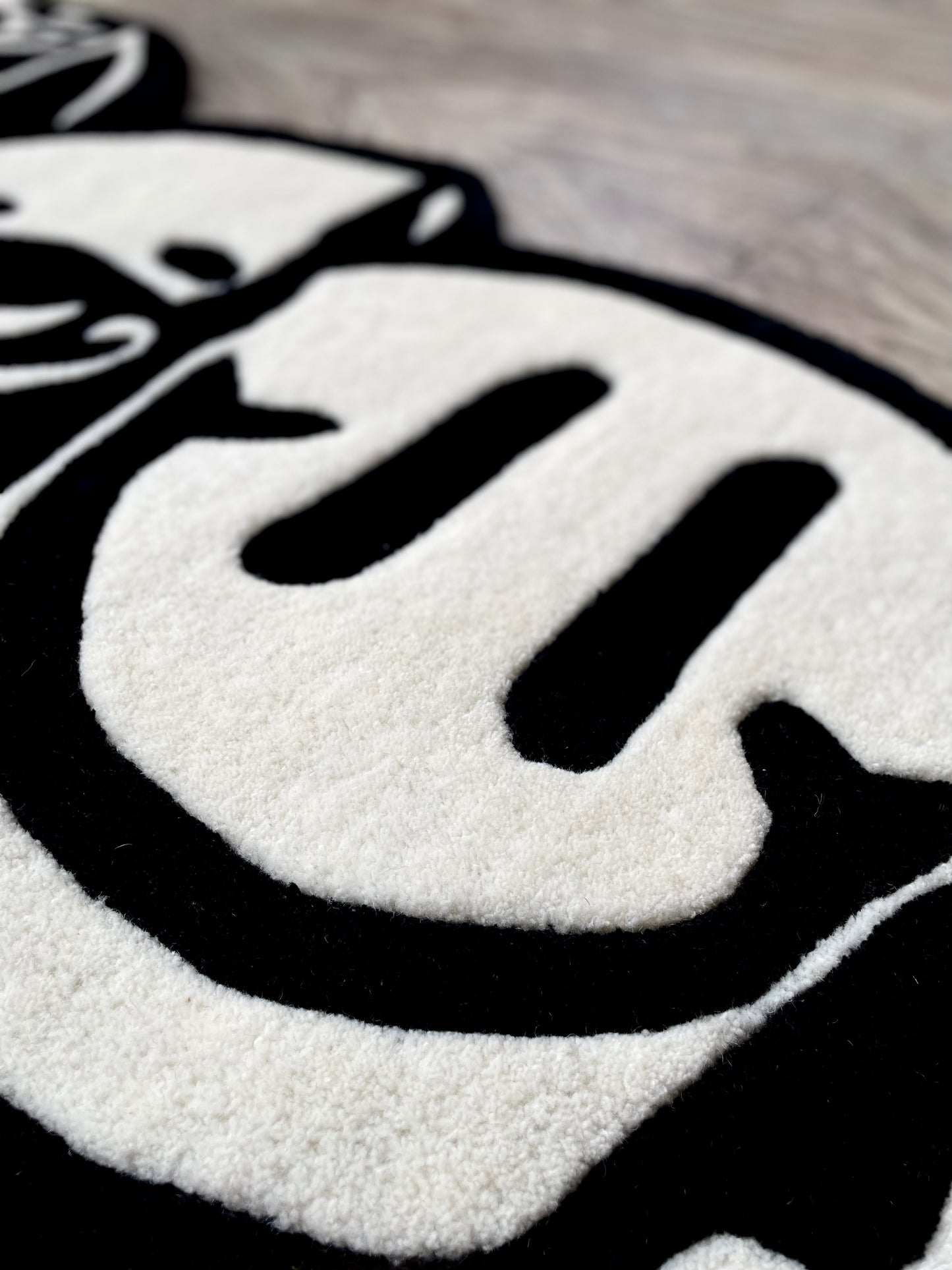 Closeup of the smiley part of the monochrome triple head tufted rug displaying crisp finish and premium wool