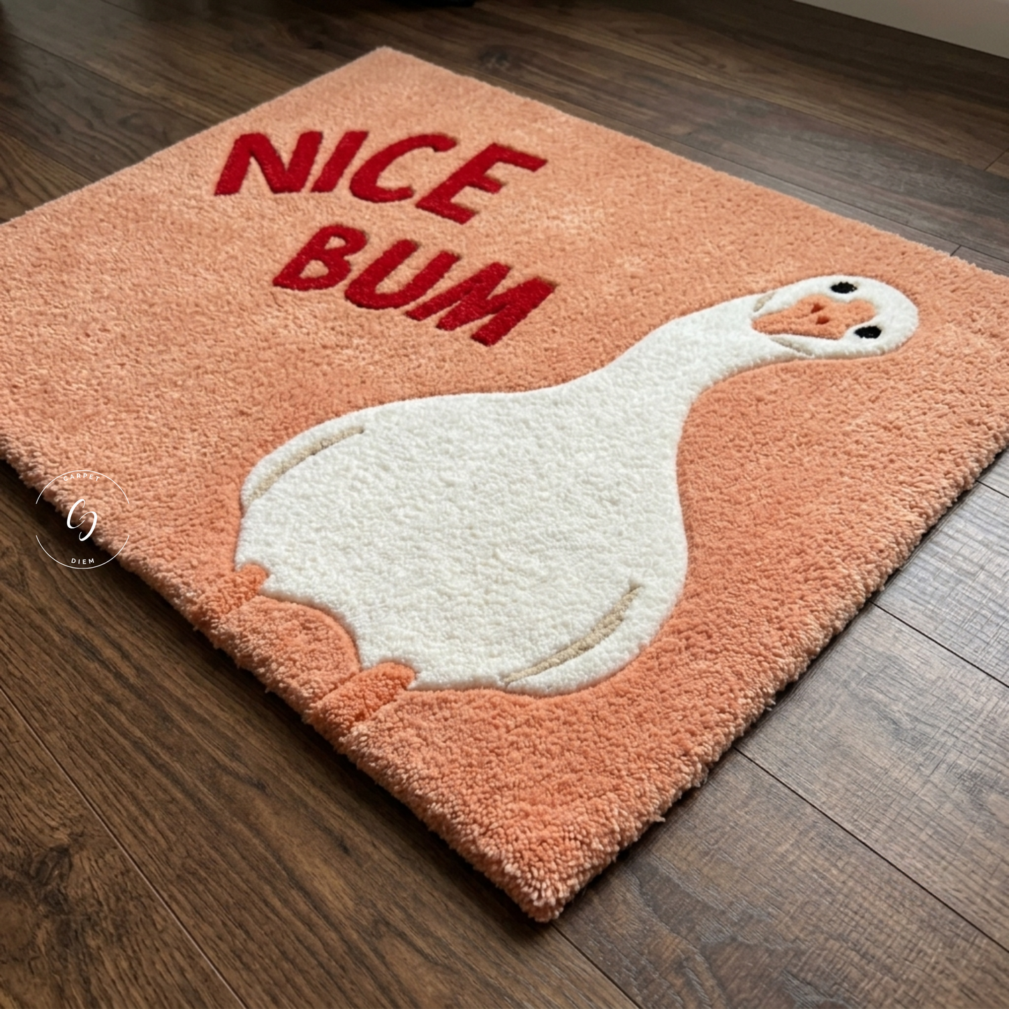 A rectangular shag tufted rug in peach-orange with a large white goose graphic and the words “NICE BUM” in red, shown on a dark wood floor.