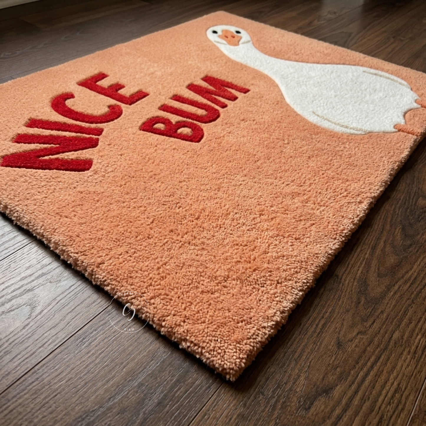A rectangular plush rug in peach-orange with red raised lettering reading 'NICE BUM' and a white duck illustration, shown on a dark wood floor.