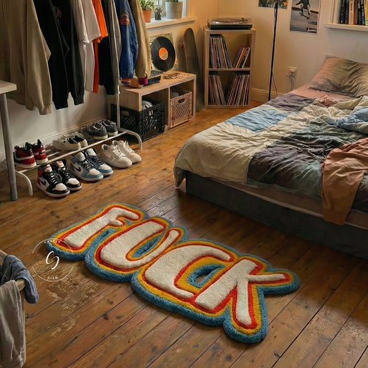 Colorful rug with the word 'FUCK' on a wooden floor in a bedroom.