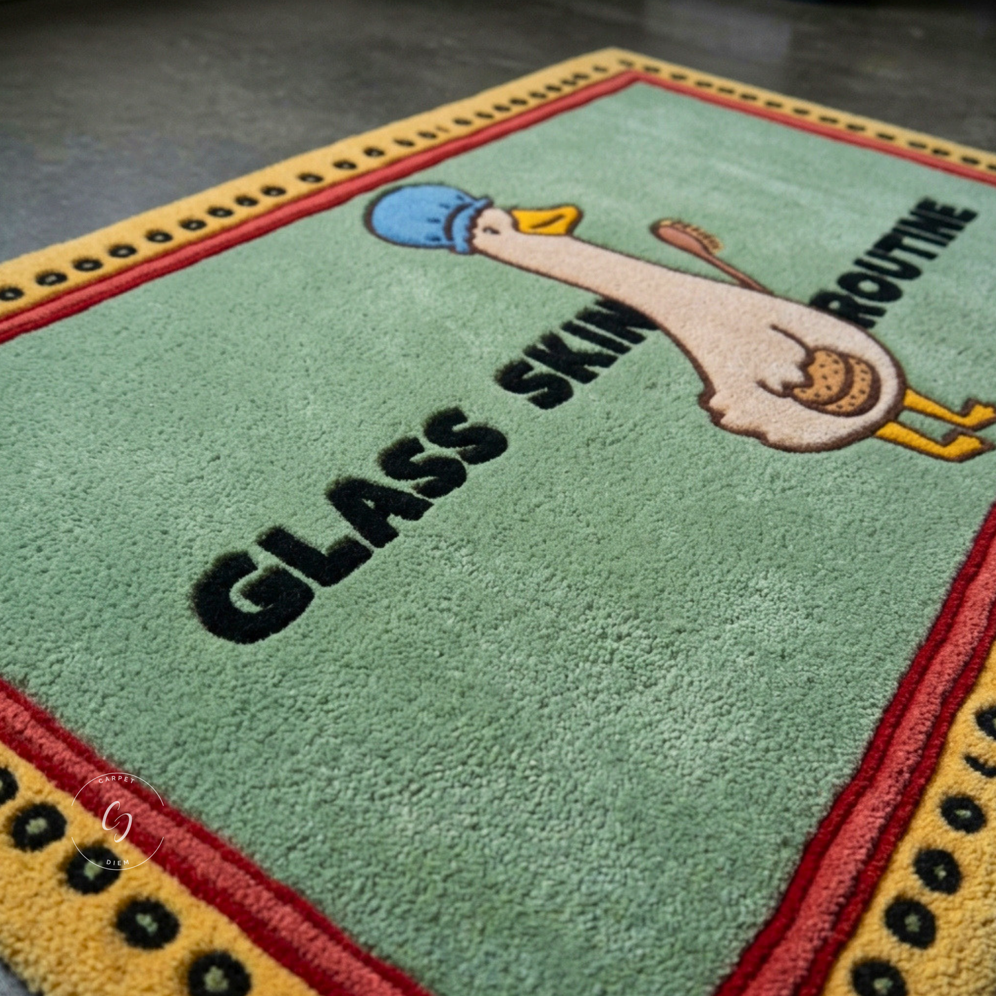 A close-up of a rectangular hand tufted bathroom entrance rug with a light green centre, red and yellow border stripes, and a cartoon goose wearing a blue beanie. The text reads 'GLASS SKIN ROUTINE' in black letters.