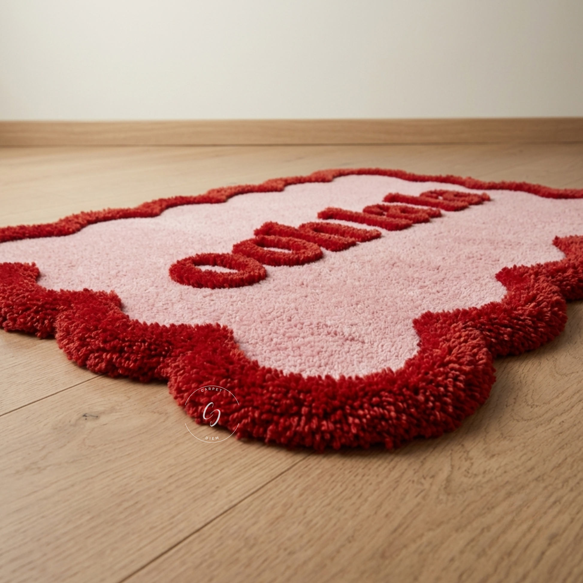 A pink and red plush hand tufted bathroom entrance rug shaped like a heart, featuring the word 'ooh la la' in raised red letters, shown on a light wood floor.