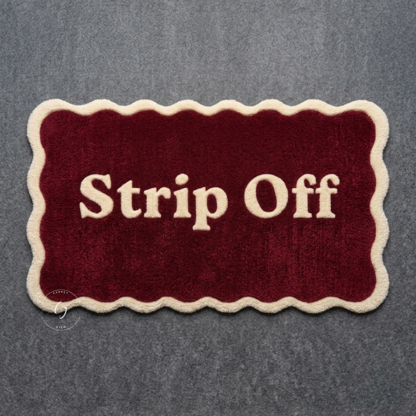 A rectangular plush hand tufted bathroom entrance rug with scalloped cream edges and the words 'Strip Off' in cream lettering on a deep burgundy background.