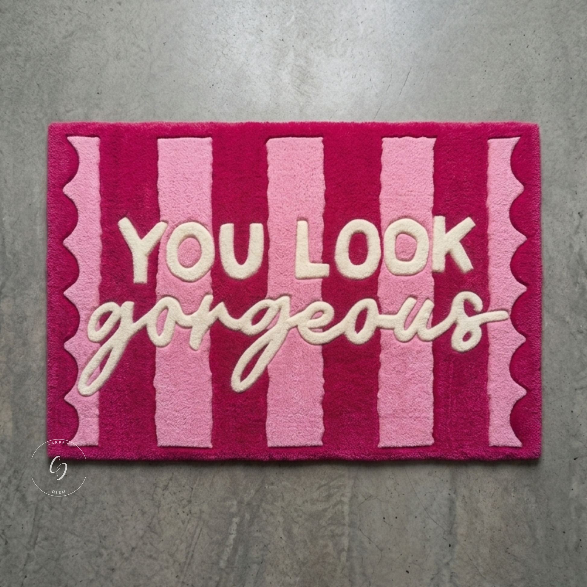A rectangular pink hand tufted bathroom entrance rug with vertical stripes in shades of pink and cream lettering that reads 'YOU LOOK gorgeous' 