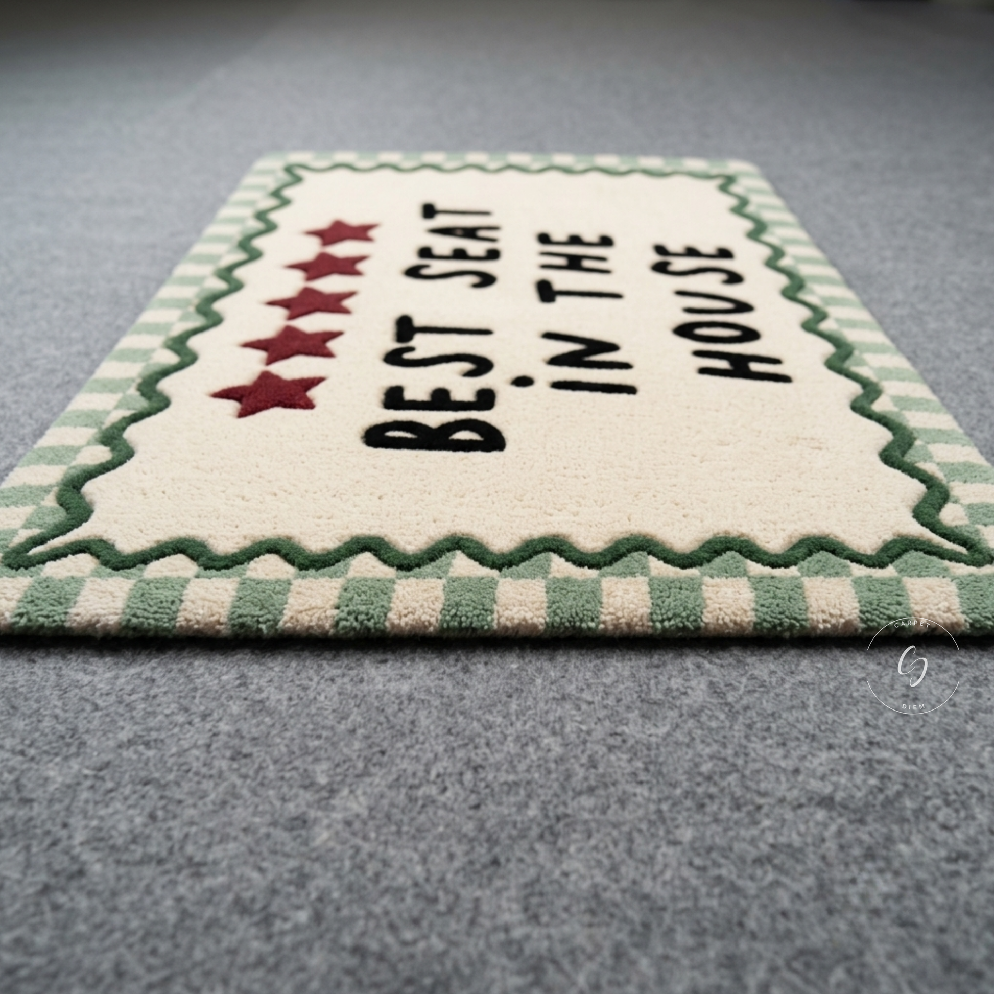 A rectangular cream-coloured hand tufted bathroom entrance rug with a green and cream checkered border, featuring the text 'BEST SEAT IN THE HOUSE' in black with five red stars