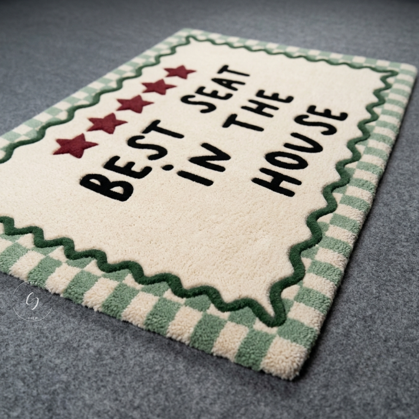 A rectangular plush hand tufted bathroom entrance rug with the phrase 'BEST SEAT IN THE HOUSE' in black text, five red stars, and a green-and-cream checkered border, photographed on a grey floor.