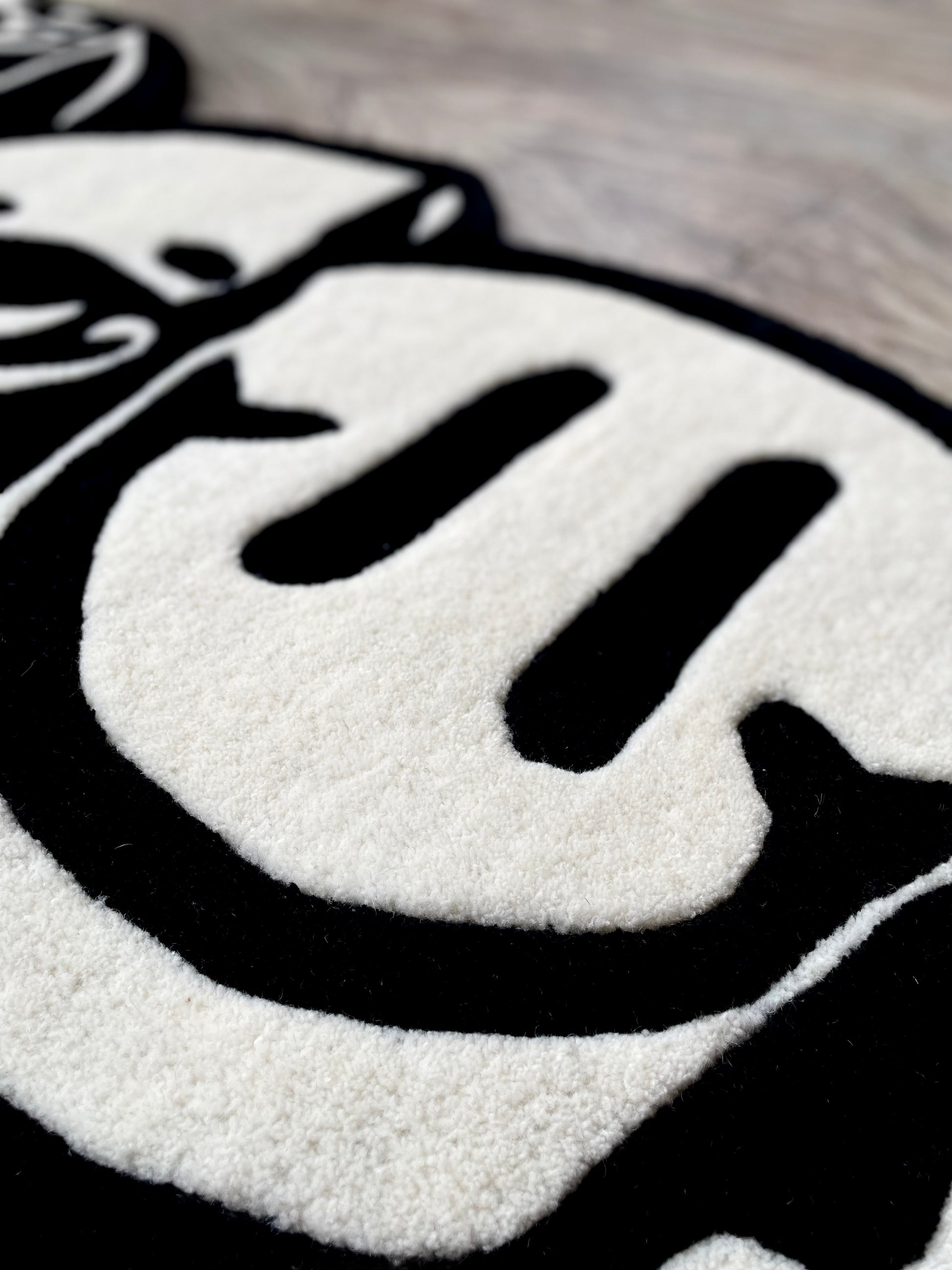 Closeup of the smiley part of the monochrome triple head tufted rug displaying crisp finish and premium wool
